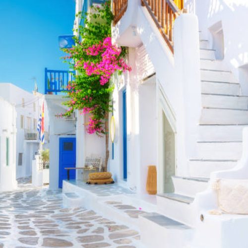 The island of Mykonos, Greece. Streets and traditional architecture. White-colored buildings and bright flowers. Travel photography.